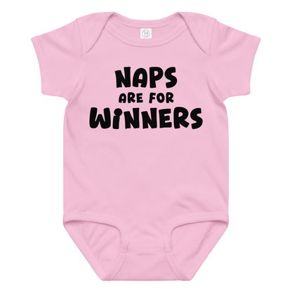 "Naps Are For Winners" printed on a pink baby jersey bodysuit laying on a flat surface amongst other clothes