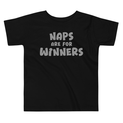 "Naps Are For Winners" printed on a black toddler short sleeve tee laying on a flat surface