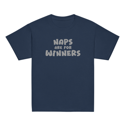 "Naps Are For Winners" printed on a navy youth classic tee laying on a flat surface