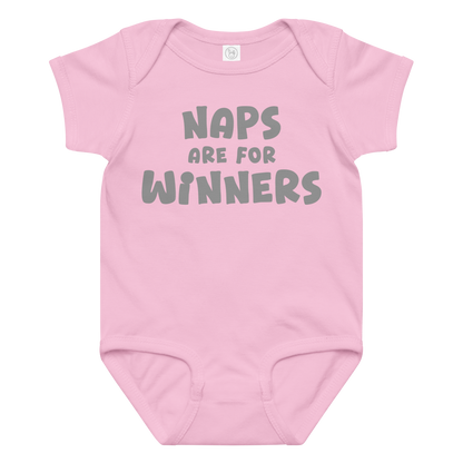 "Naps Are For Winners" printed on a pink baby jersey bodysuit laying on a flat surface amongst other clothes