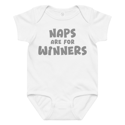 "Naps Are For Winners" printed on a white baby jersey bodysuit laying on a flat surface amongst other clothes