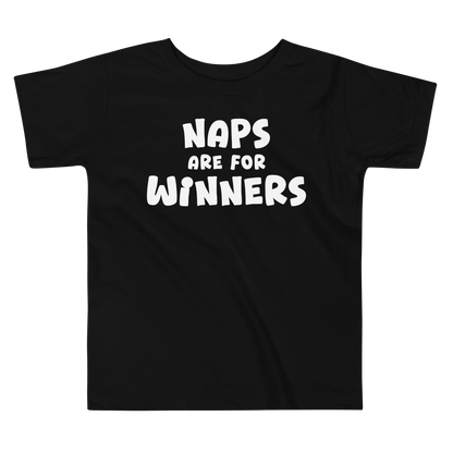 "Naps Are For Winners" printed on a black toddler short sleeve tee laying on a flat surface