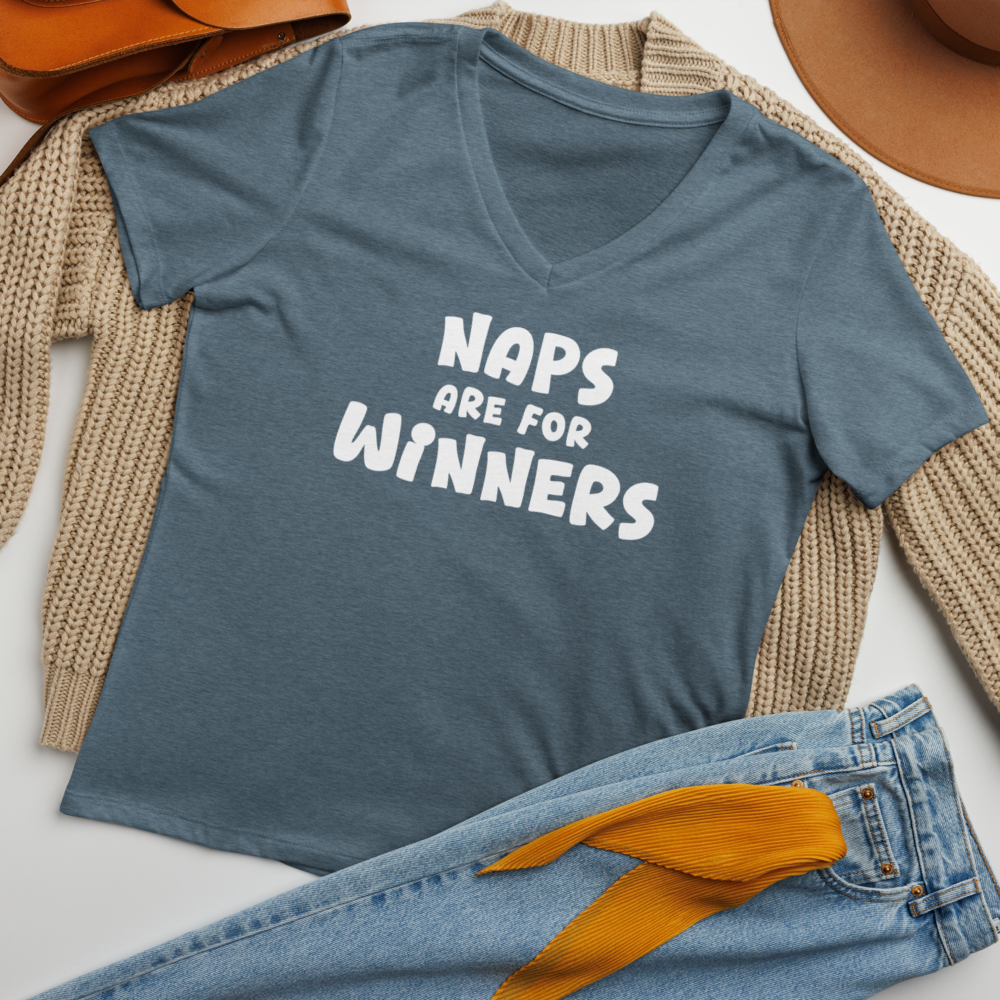 "Naps Are For Winners" printed on a heather slate women's relaxed v-neck t-shirt laying on a flat surface amongst other clothes