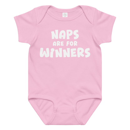 "Naps Are For Winners" printed on a pink baby jersey bodysuit laying on a flat surface amongst other clothes