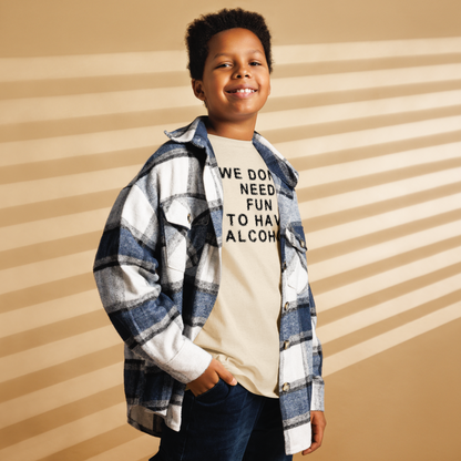 "We don’t need fun to have alcohol" printed on a natural youth classic tee worn by a male also wearing a jacket