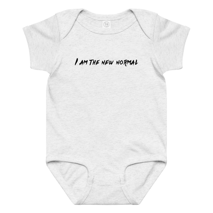"I am the new normal" printed on a ash baby jersey bodysuit laying on a flat surface amongst other clothes