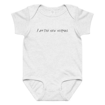 "I am the new normal" printed on a ash baby jersey bodysuit laying on a flat surface amongst other clothes