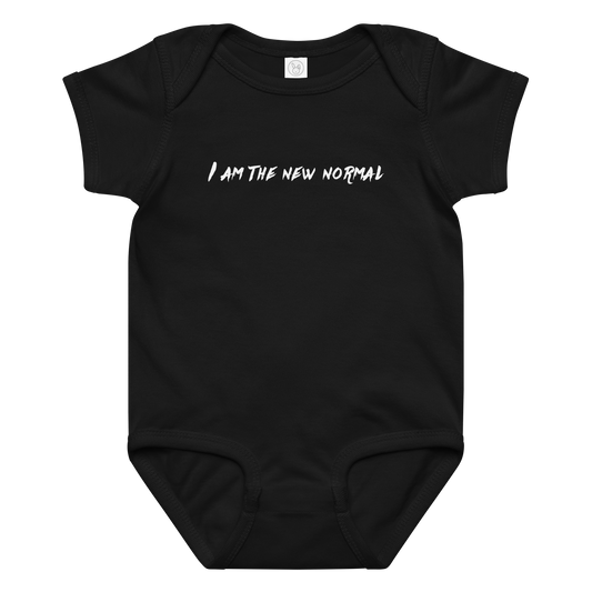 "I am the new normal" printed on a black baby jersey bodysuit laying on a flat surface amongst other clothes