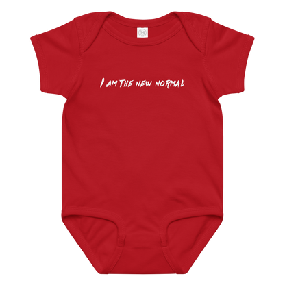 "I am the new normal" printed on a red baby jersey bodysuit laying on a flat surface amongst other clothes