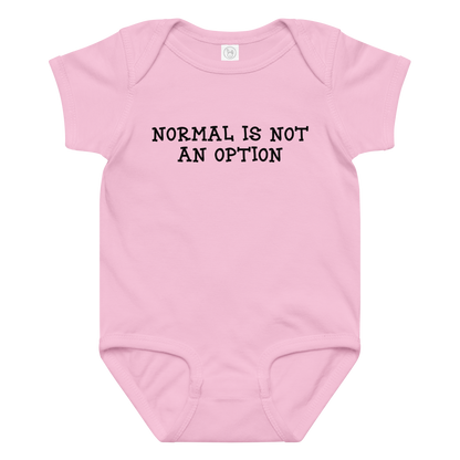 "Normal is not an option" printed on a pink baby jersey bodysuit laying on a flat surface amongst other clothes