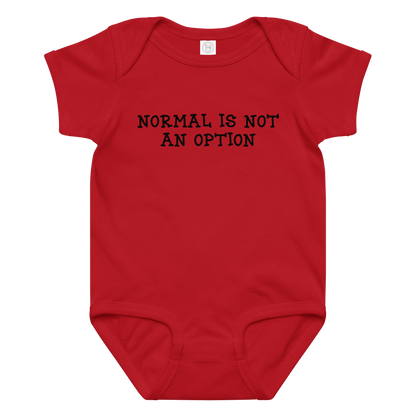 "Normal is not an option" printed on a red baby jersey bodysuit laying on a flat surface amongst other clothes