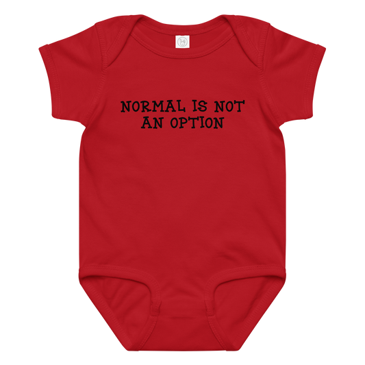 "Normal is not an option" printed on a red baby jersey bodysuit laying on a flat surface amongst other clothes