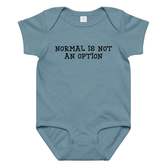 "Normal is not an option" printed on a vintage indigo baby jersey bodysuit laying on a flat surface amongst other clothes