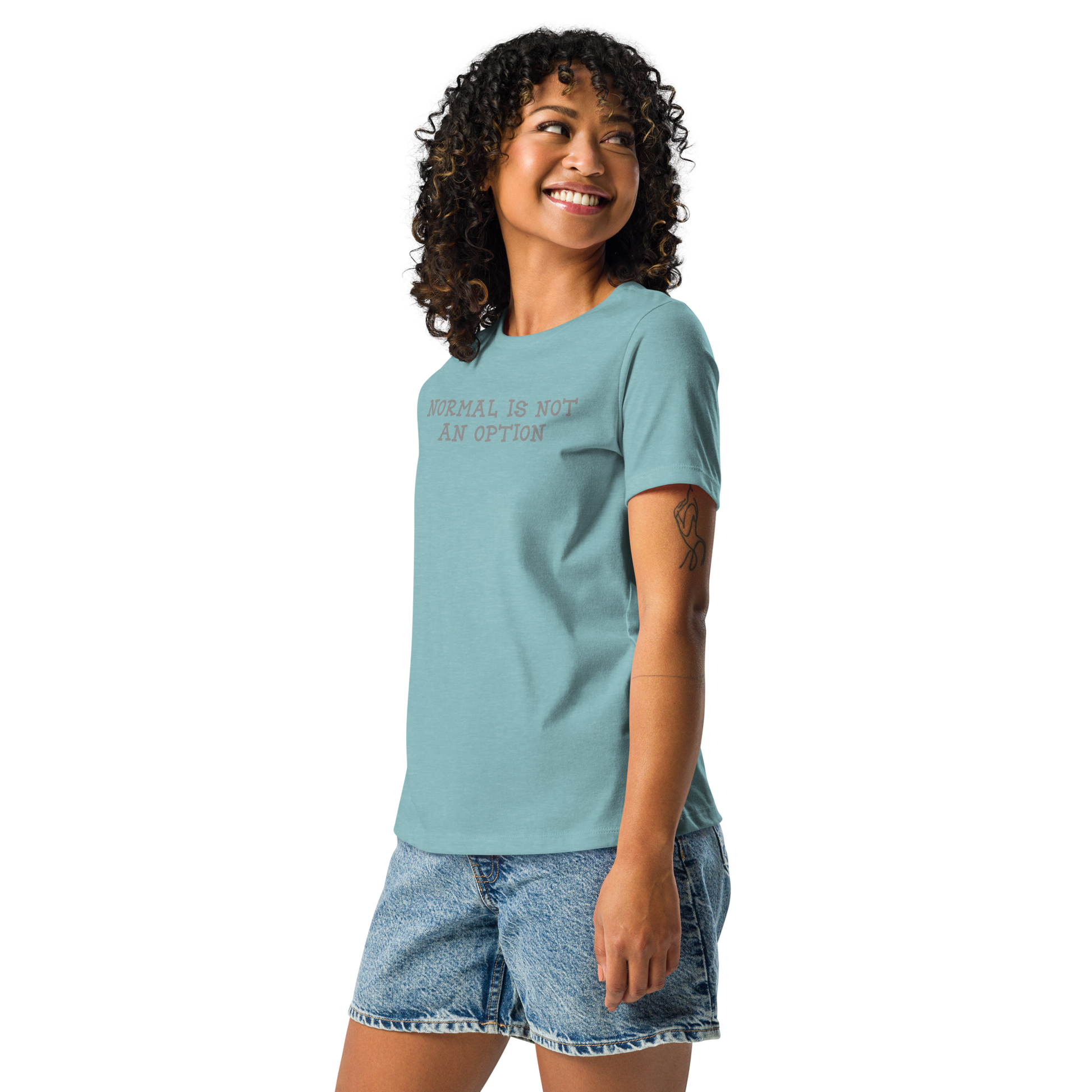 "Normal is not an option" printed on a heather blue lagoon women's relaxed t-shirt worn by a female