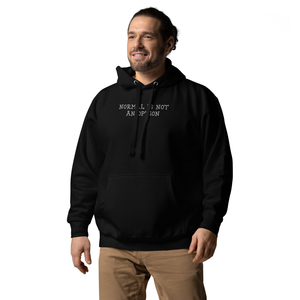"Normal is not an option" printed on a black unisex hoodie worn by a male