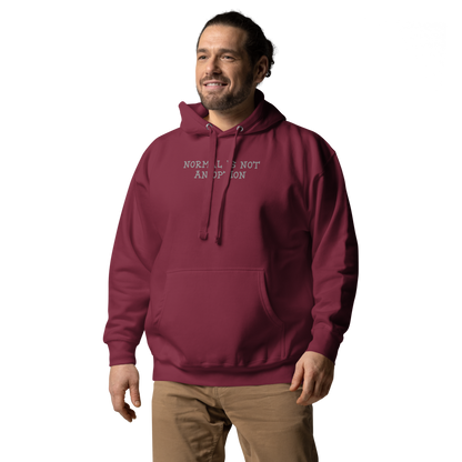 "Normal is not an option" printed on a maroon unisex hoodie worn by a male