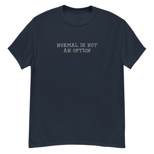 "Normal is not an option" printed on a navy unisex classic tee laying on a flat surface