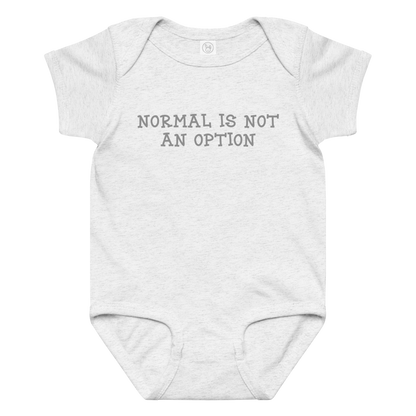 "Normal is not an option" printed on a ash baby jersey bodysuit laying on a flat surface amongst other clothes