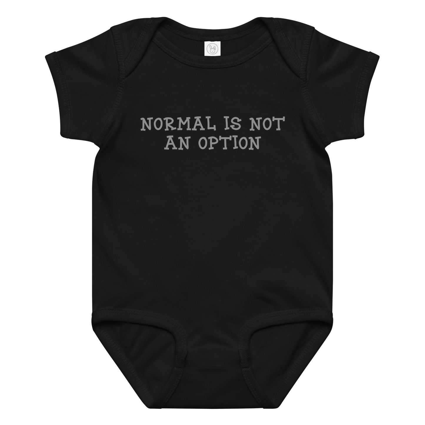 "Normal is not an option" printed on a black baby jersey bodysuit laying on a flat surface amongst other clothes