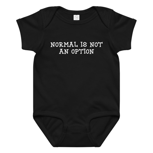 "Normal is not an option" printed on a black baby jersey bodysuit laying on a flat surface amongst other clothes