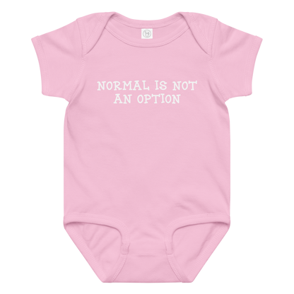 "Normal is not an option" printed on a pink baby jersey bodysuit laying on a flat surface amongst other clothes