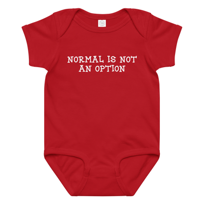 "Normal is not an option" printed on a red baby jersey bodysuit laying on a flat surface amongst other clothes