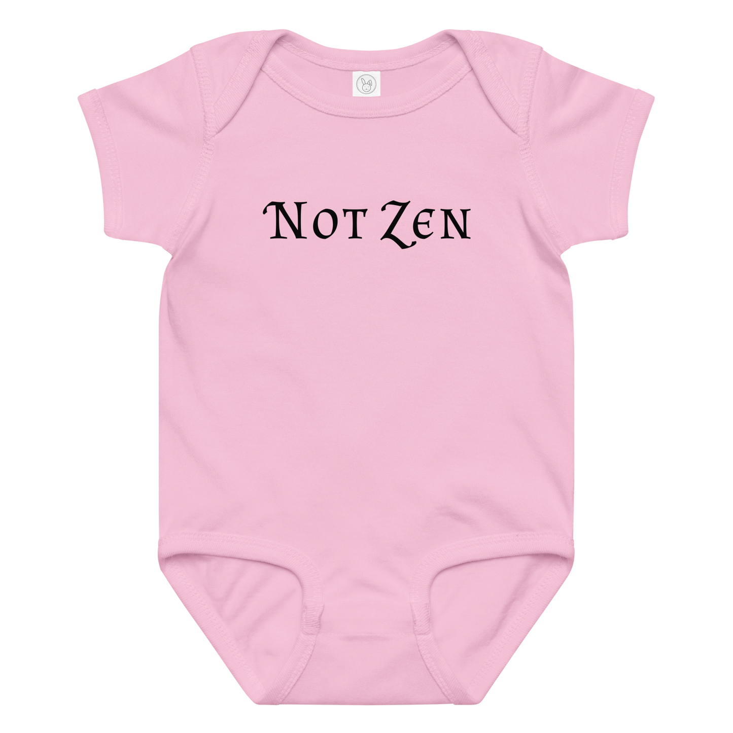 "Not zen" printed on a pink baby jersey bodysuit laying on a flat surface amongst other clothes