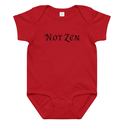 "Not zen" printed on a red baby jersey bodysuit laying on a flat surface amongst other clothes