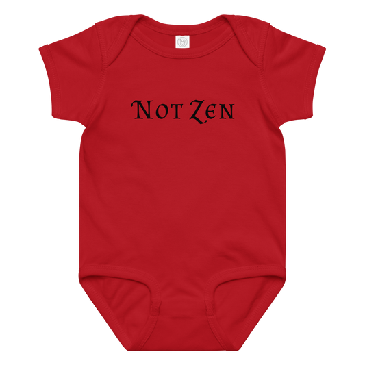"Not zen" printed on a red baby jersey bodysuit laying on a flat surface amongst other clothes