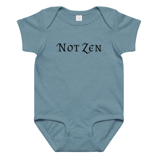 "Not zen" printed on a vintage indigo baby jersey bodysuit laying on a flat surface amongst other clothes