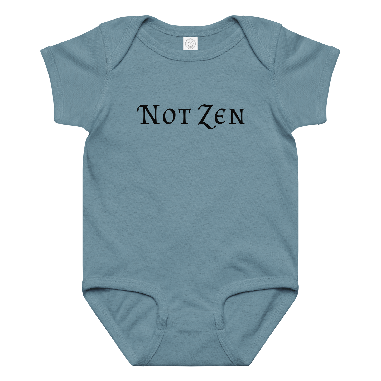 "Not zen" printed on a vintage indigo baby jersey bodysuit laying on a flat surface amongst other clothes