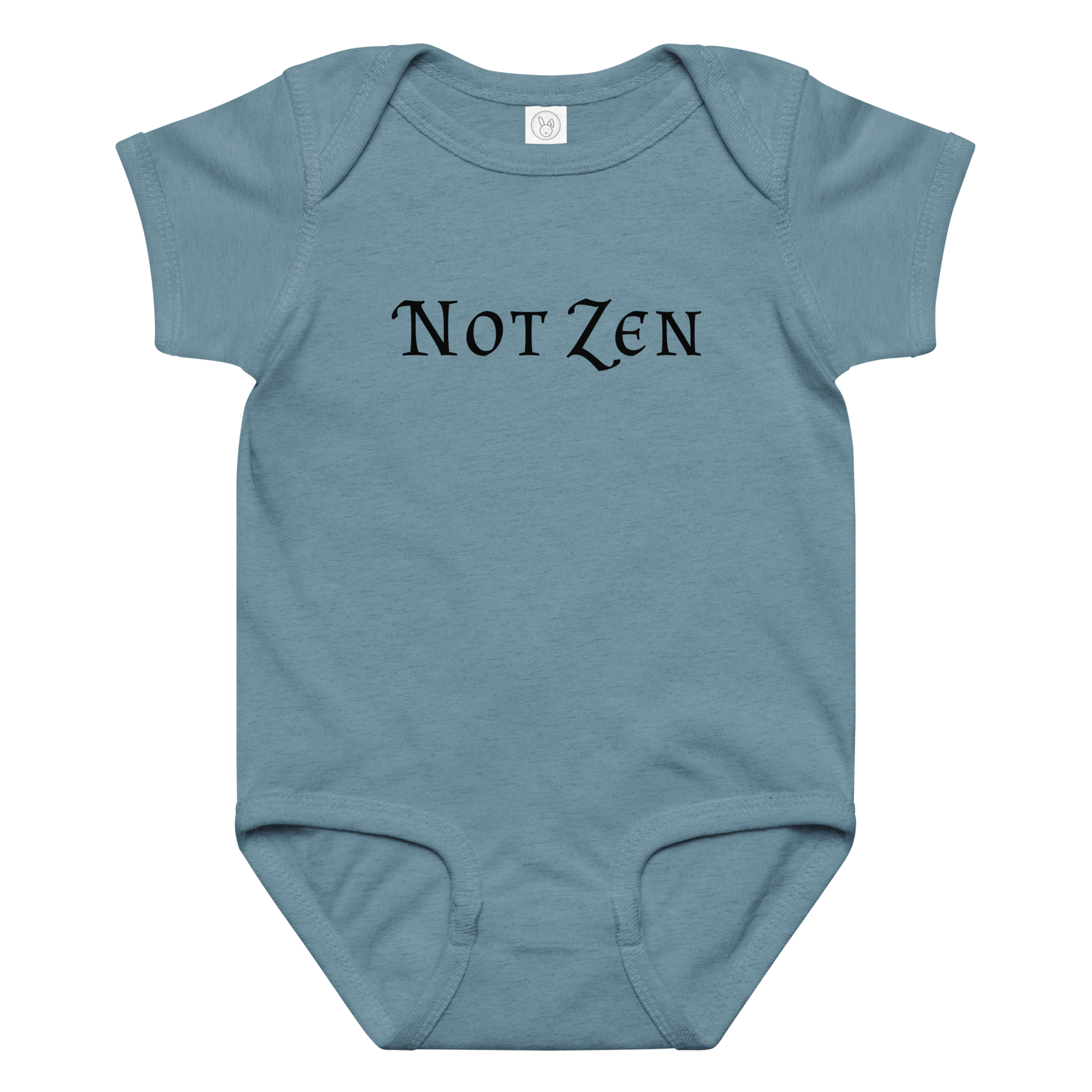 "Not zen" printed on a vintage indigo baby jersey bodysuit laying on a flat surface amongst other clothes