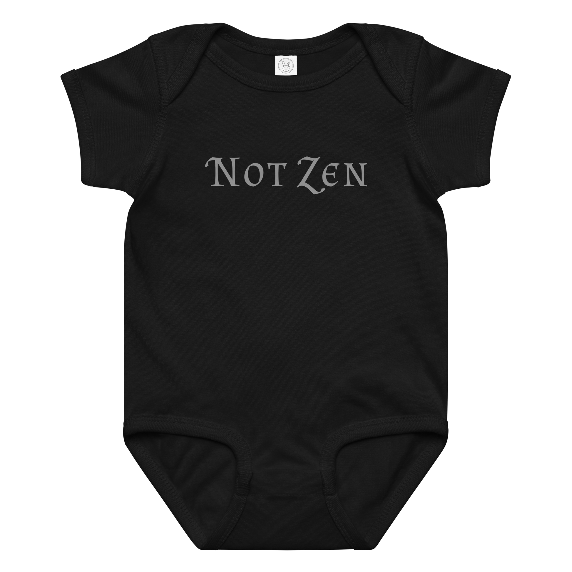 "Not zen" printed on a black baby jersey bodysuit laying on a flat surface amongst other clothes