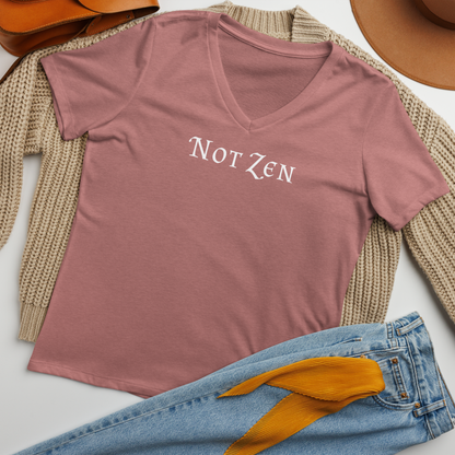 "Not zen" printed on a heather mauve women's relaxed v-neck t-shirt laying on a flat surface amongst other clothes