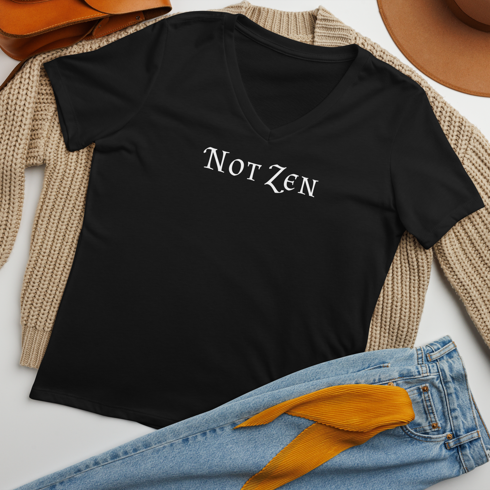 "Not zen" printed on a solid black blend women's relaxed v-neck t-shirt laying on a flat surface amongst other clothes