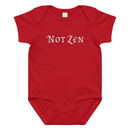 "Not zen" printed on a red baby jersey bodysuit laying on a flat surface amongst other clothes