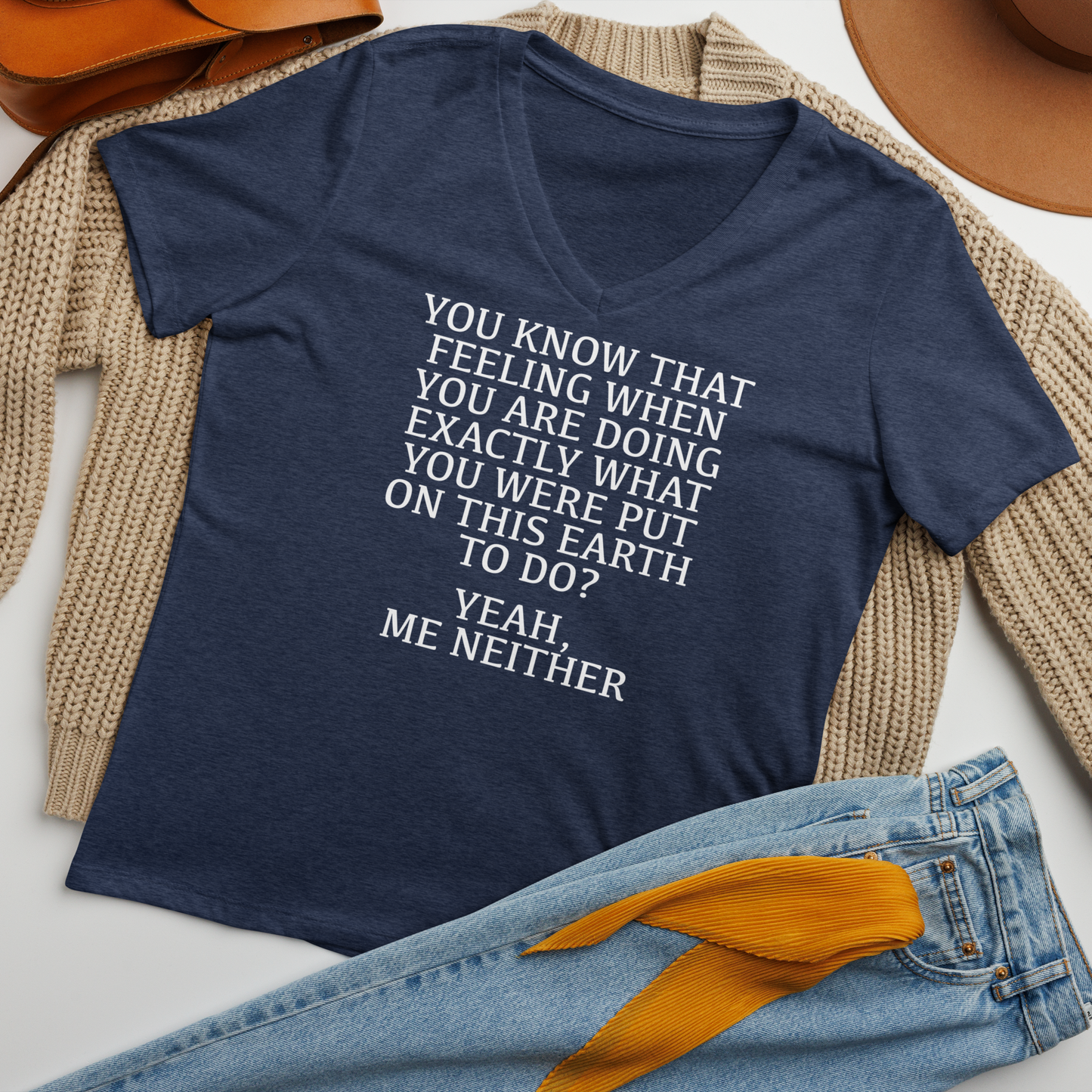 "You know that feeling when you are doing exactly what you were put on this earth to do? Yeah, Me Neither" printed on a heather navy women's relaxed v-neck t-shirt laying on a flat surface amongst other clothes
