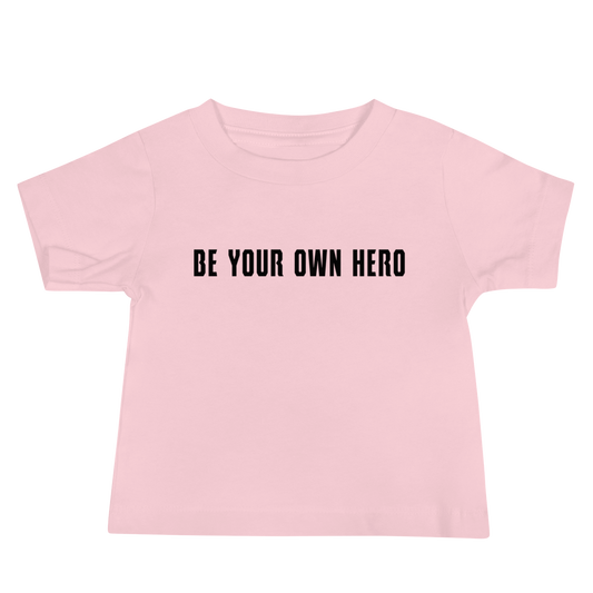 "Be your own here" printed on a pink baby jersey short sleeve tee laying on a flat surface