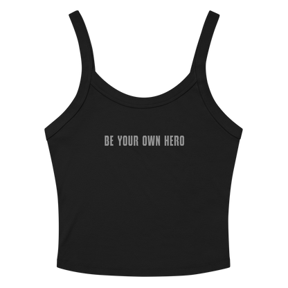 "Be your own here" printed on a solid black blend women's micro-rib tanktop laying on a flat surface amongst sunglasses and shorts