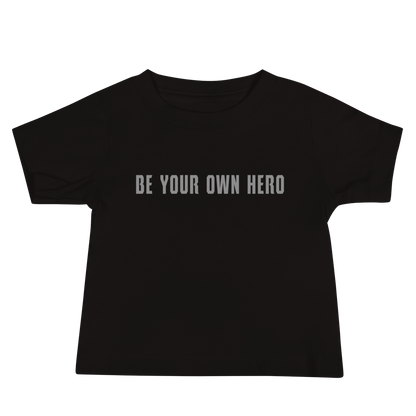 "Be your own here" printed on a black baby jersey short sleeve tee laying on a flat surface