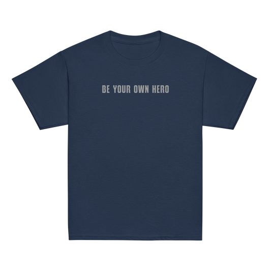 "Be your own here" printed on a navy youth classic tee laying on a flat surface