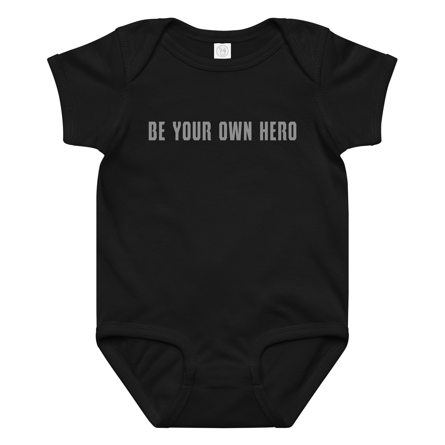 "Be your own here" printed on a black baby jersey bodysuit laying on a flat surface amongst other clothes