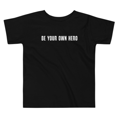 "Be your own here" printed on a black toddler short sleeve tee laying on a flat surface