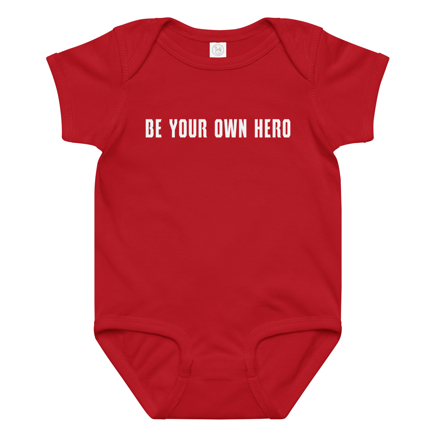 "Be your own here" printed on a red baby jersey bodysuit laying on a flat surface amongst other clothes
