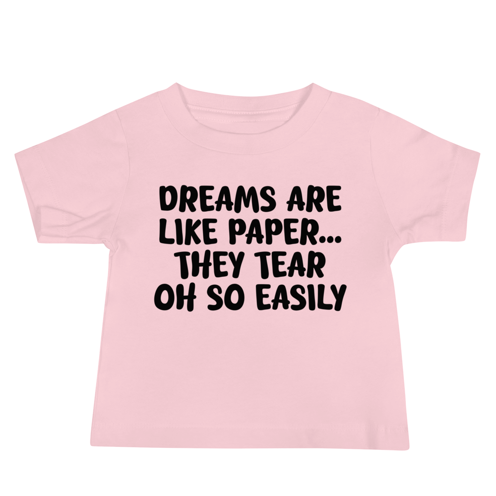 "Dreams are like paper, they tear oh so easily" printed on a pink baby jersey short sleeve tee laying on a flat surface