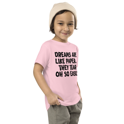 "Dreams are like paper, they tear oh so easily" printed on a pink toddler short sleeve tee worn by a male who is also wearing a knit cap