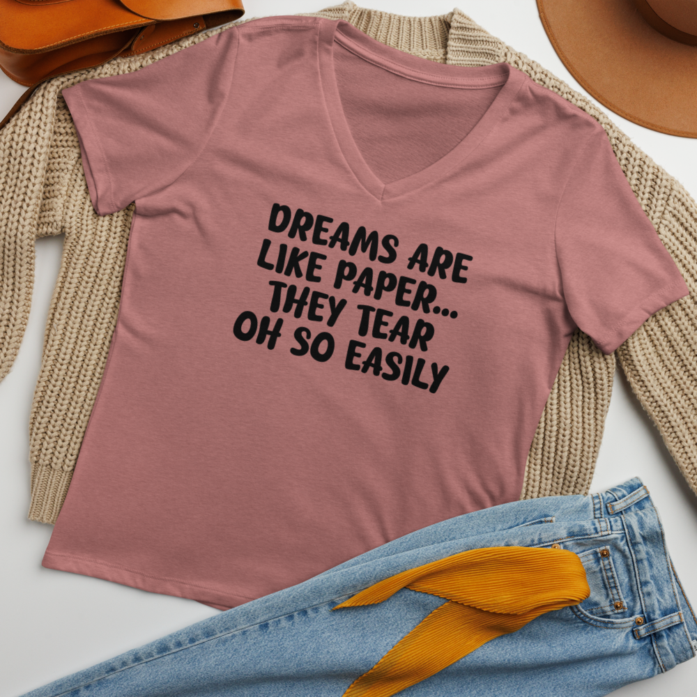 "Dreams are like paper, they tear oh so easily" printed on a heather mauve women's relaxed v-neck t-shirt laying on a flat surface amongst other clothes