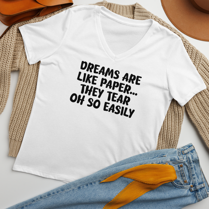 "Dreams are like paper, they tear oh so easily" printed on a solid white blend women's relaxed v-neck t-shirt laying on a flat surface amongst other clothes