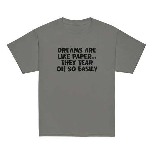 "Dreams are like paper, they tear oh so easily" printed on a charcoal youth classic tee laying on a flat surface