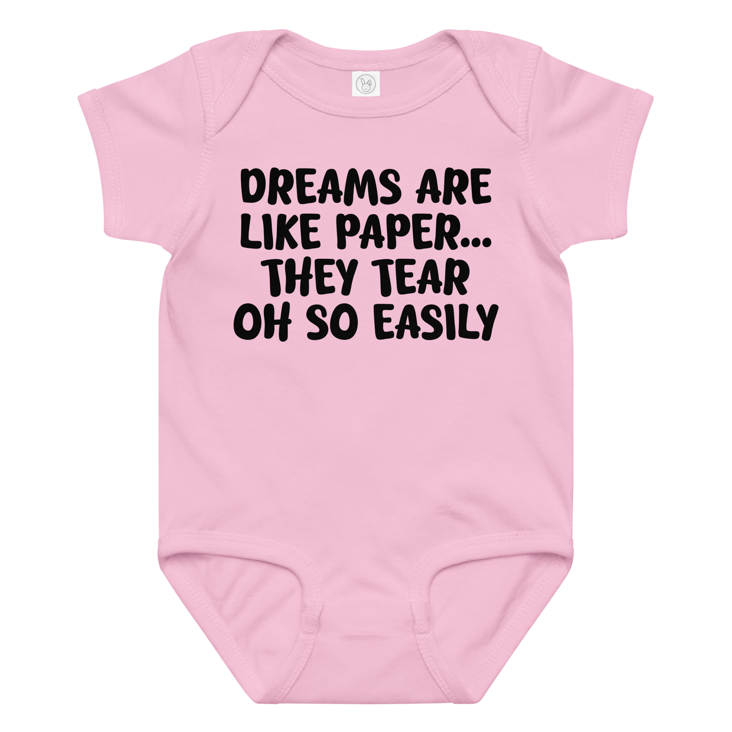 "Dreams are like paper, they tear oh so easily" printed on a pink baby jersey bodysuit laying on a flat surface amongst other clothes